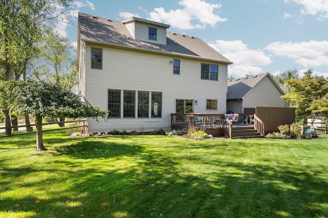 back of property with a lawn, a wooden deck, and fence