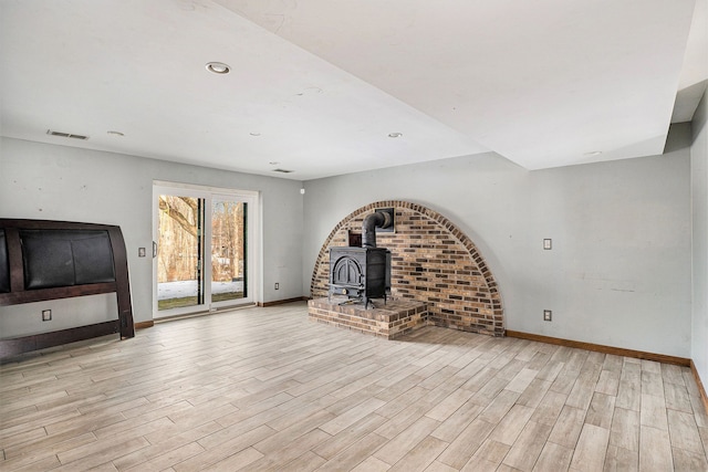 unfurnished living room with recessed lighting, wood finished floors, visible vents, baseboards, and a wood stove