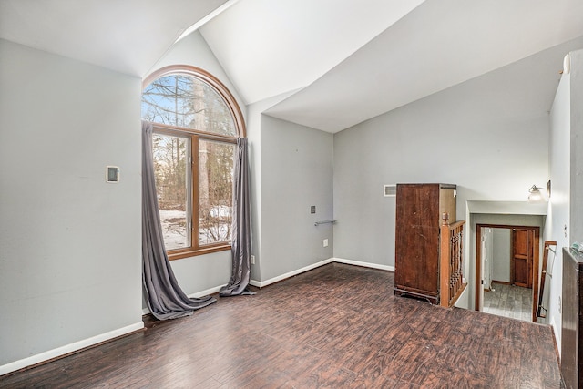 empty room with vaulted ceiling, wood finished floors, visible vents, and baseboards