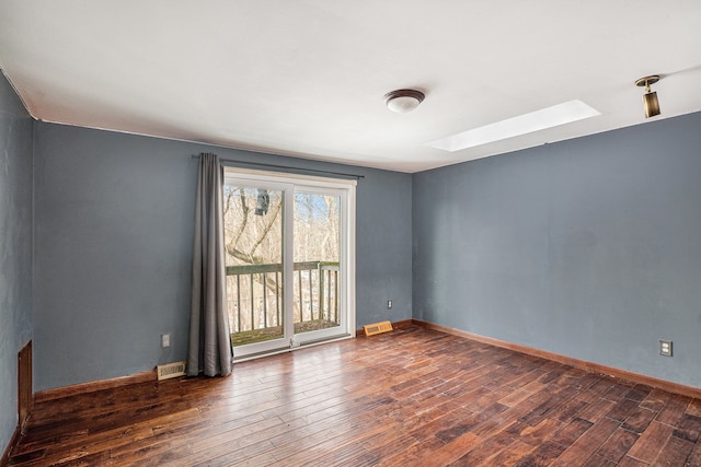 unfurnished room with a skylight, baseboards, visible vents, and hardwood / wood-style floors