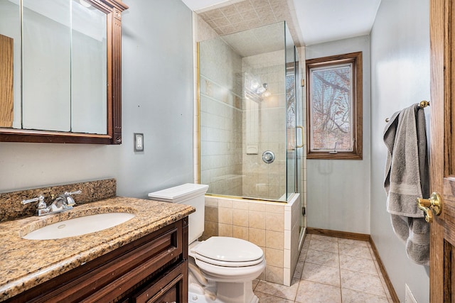 full bathroom with toilet, vanity, tile patterned flooring, tiled shower, and baseboards