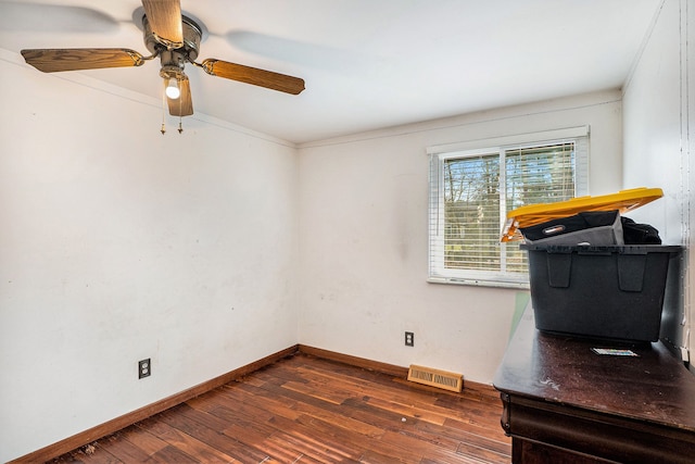 unfurnished office featuring wood finished floors, a ceiling fan, visible vents, baseboards, and ornamental molding