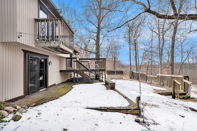 snowy yard with stairs and a wooden deck