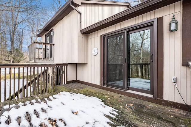 snow covered property entrance featuring a deck