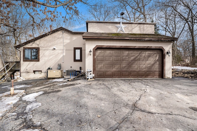 view of front of home featuring a garage, cooling unit, and driveway