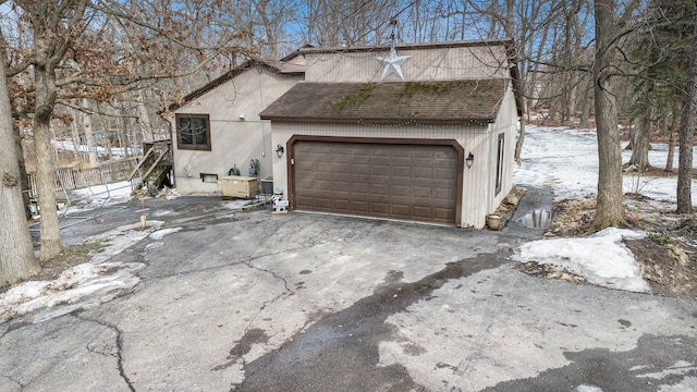 exterior space with a garage and a shingled roof