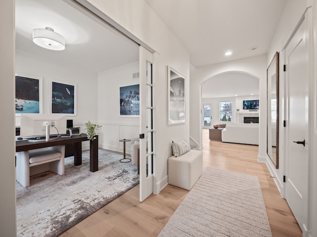 hall with recessed lighting, arched walkways, and light wood-style flooring