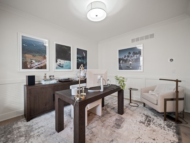 home office featuring a decorative wall, light wood-type flooring, visible vents, and ornamental molding