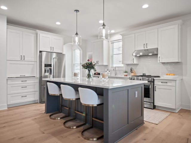 kitchen featuring under cabinet range hood, white cabinetry, a center island, and stainless steel appliances