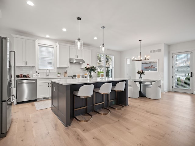 kitchen with visible vents, a center island, stainless steel appliances, white cabinets, and light countertops