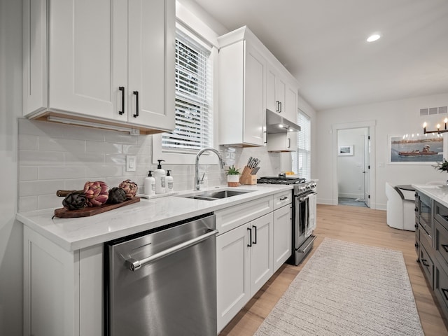 kitchen featuring visible vents, a sink, under cabinet range hood, appliances with stainless steel finishes, and light wood finished floors