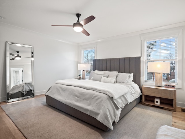 bedroom featuring baseboards, wood finished floors, a ceiling fan, and ornamental molding