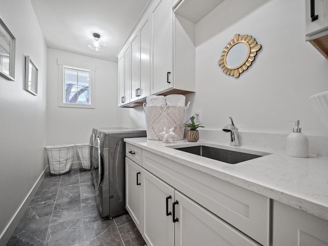 laundry area featuring marble finish floor, a sink, cabinet space, baseboards, and washing machine and clothes dryer