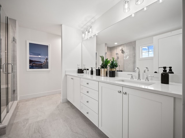 full bath with double vanity, a shower stall, baseboards, and a sink