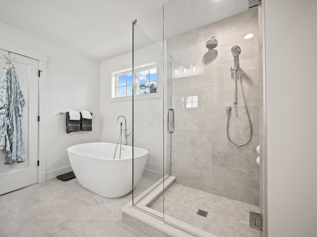 bathroom with a shower stall, a freestanding bath, and baseboards