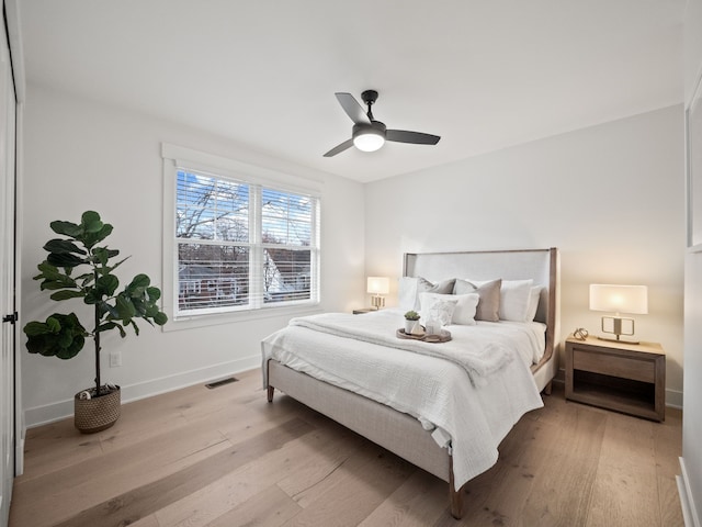 bedroom featuring visible vents, a ceiling fan, baseboards, and wood finished floors