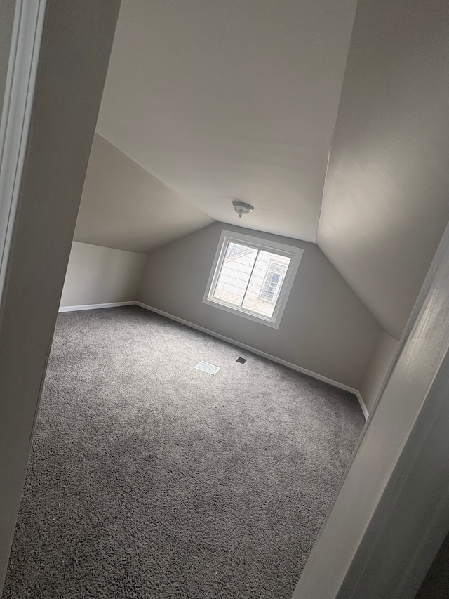 bonus room featuring baseboards, visible vents, vaulted ceiling, and carpet flooring