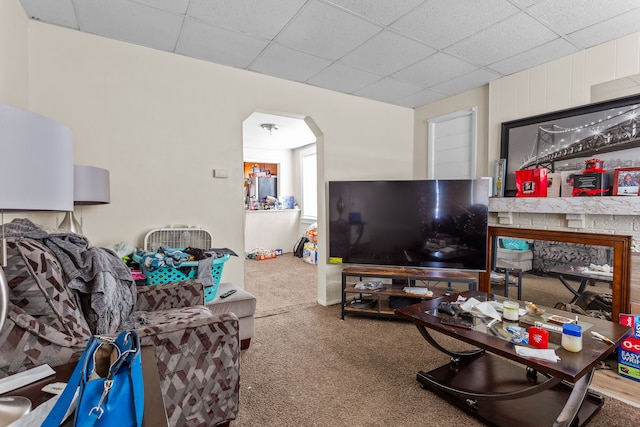 living room featuring carpet flooring, arched walkways, and a drop ceiling