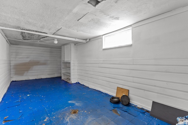 below grade area with wood walls and a textured ceiling