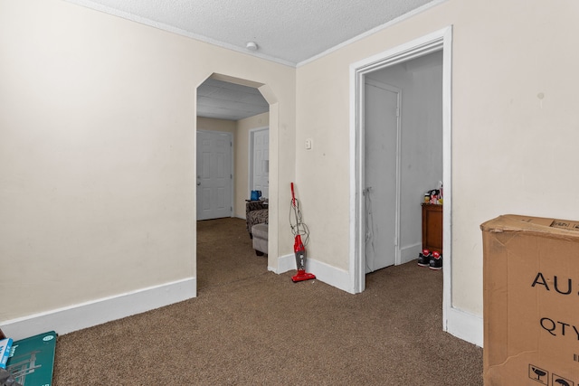 carpeted spare room featuring baseboards, arched walkways, and a textured ceiling