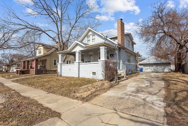 view of side of home with covered porch, a chimney, a detached garage, and an outdoor structure