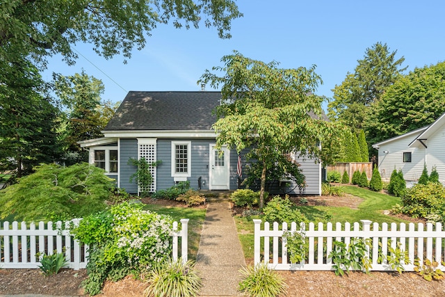 view of front of home with a shingled roof and fence