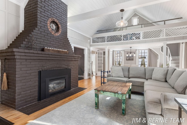 living area with a brick fireplace, wood finished floors, high vaulted ceiling, and beamed ceiling