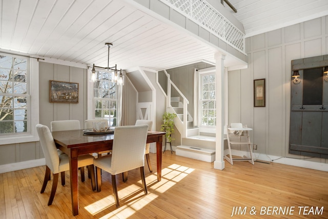 dining area with stairs, decorative columns, a decorative wall, a chandelier, and light wood finished floors