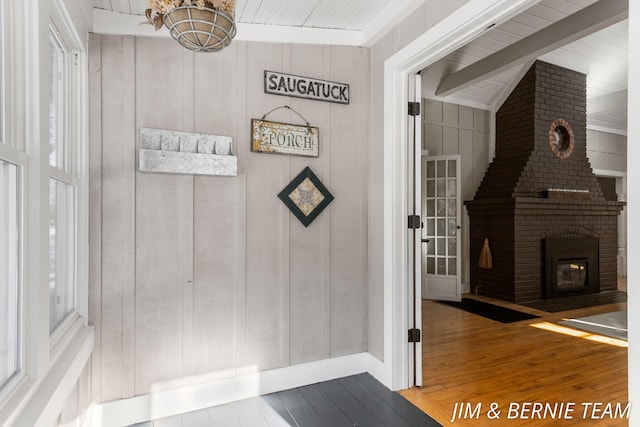 interior space with a brick fireplace, a notable chandelier, hardwood / wood-style floors, and beamed ceiling