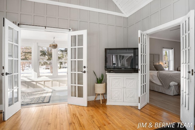 doorway to outside with a chandelier, french doors, hardwood / wood-style flooring, and a decorative wall
