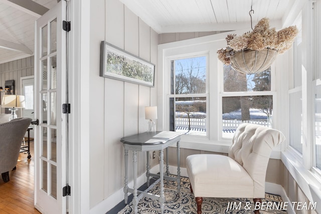 interior space featuring wood ceiling, beam ceiling, a decorative wall, and wood finished floors