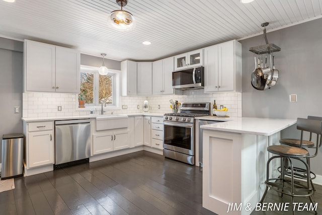 kitchen with appliances with stainless steel finishes, wood ceiling, a peninsula, and white cabinetry