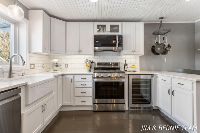 kitchen with appliances with stainless steel finishes, white cabinets, and beverage cooler