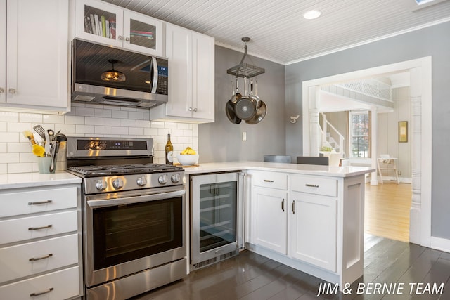 kitchen with a peninsula, appliances with stainless steel finishes, dark wood-type flooring, and wine cooler