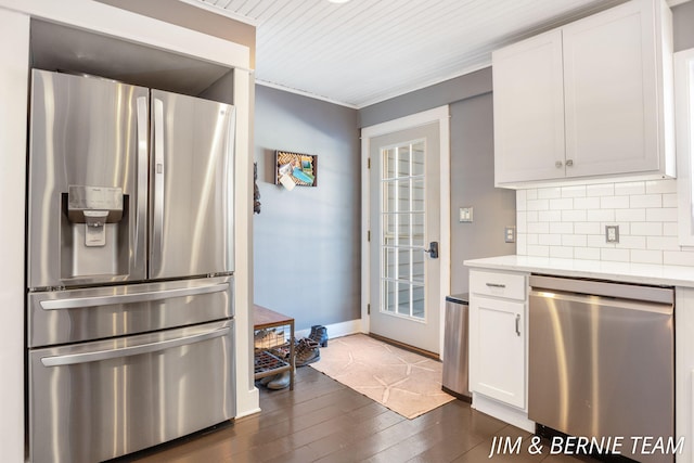 kitchen with dark wood-style flooring, stainless steel appliances, baseboards, white cabinetry, and backsplash