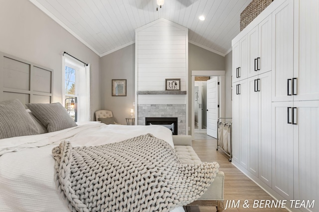 bedroom featuring crown molding, a fireplace, vaulted ceiling, and light wood-type flooring