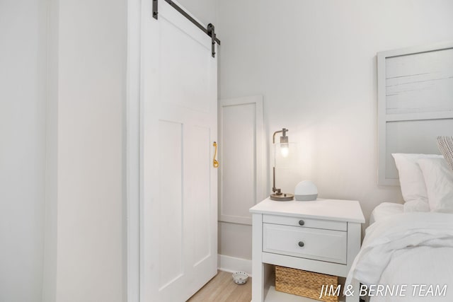 bedroom with a barn door and light wood finished floors