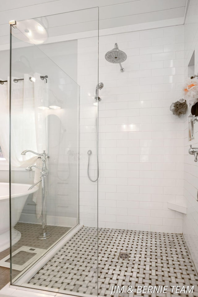 full bath with tile patterned flooring, a freestanding bath, and a stall shower