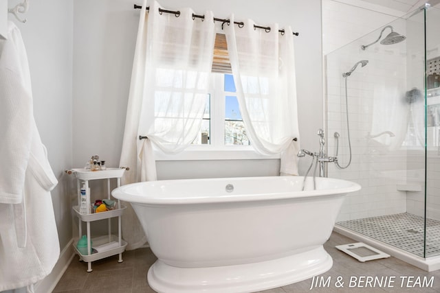 bathroom featuring tile patterned floors, a freestanding tub, and a stall shower