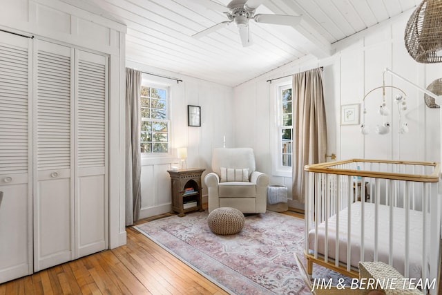 bedroom featuring wood ceiling, a crib, hardwood / wood-style floors, and multiple windows