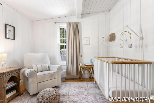 sitting room featuring wood ceiling, a decorative wall, wood finished floors, and beam ceiling