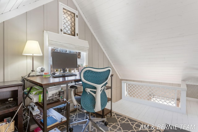 home office featuring vaulted ceiling and a decorative wall