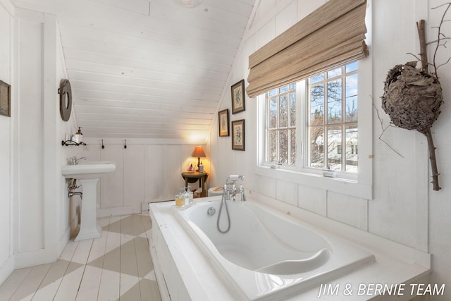 bathroom featuring tile patterned flooring, a bath, and lofted ceiling