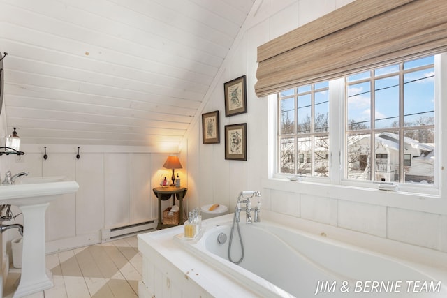 bathroom with a garden tub, a sink, tile patterned floors, a baseboard radiator, and lofted ceiling