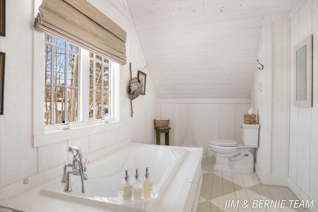 full bath with a garden tub, tile patterned flooring, a decorative wall, toilet, and vaulted ceiling