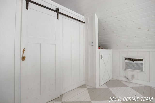 laundry area featuring light tile patterned floors, an AC wall unit, and a barn door