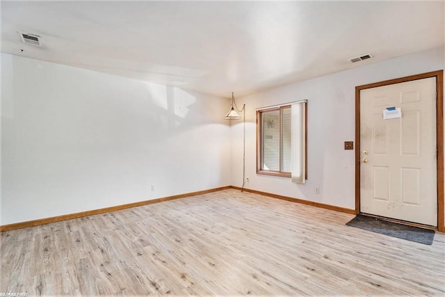 foyer with light wood-style floors, visible vents, and baseboards