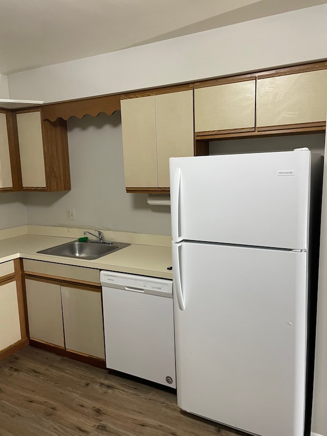 kitchen featuring wood finished floors, light countertops, white appliances, and a sink