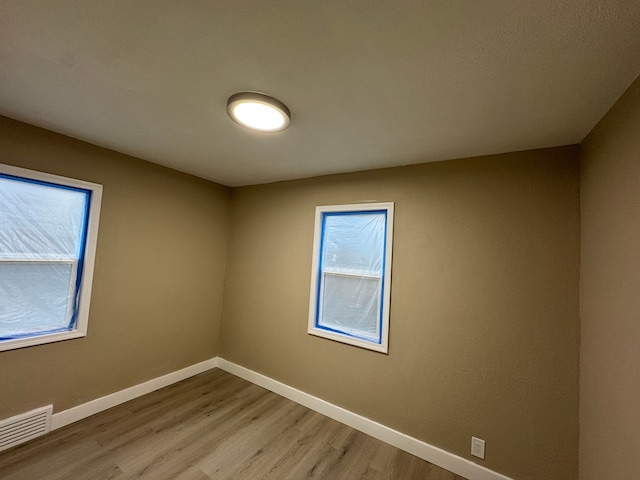 unfurnished room with baseboards, visible vents, and wood finished floors