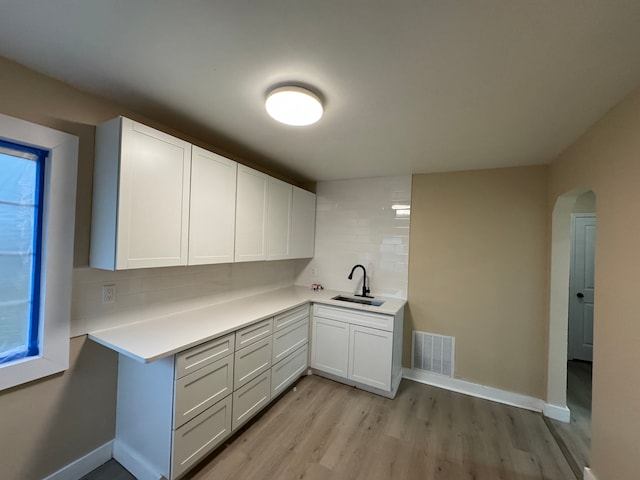 kitchen with visible vents, decorative backsplash, a sink, and light countertops